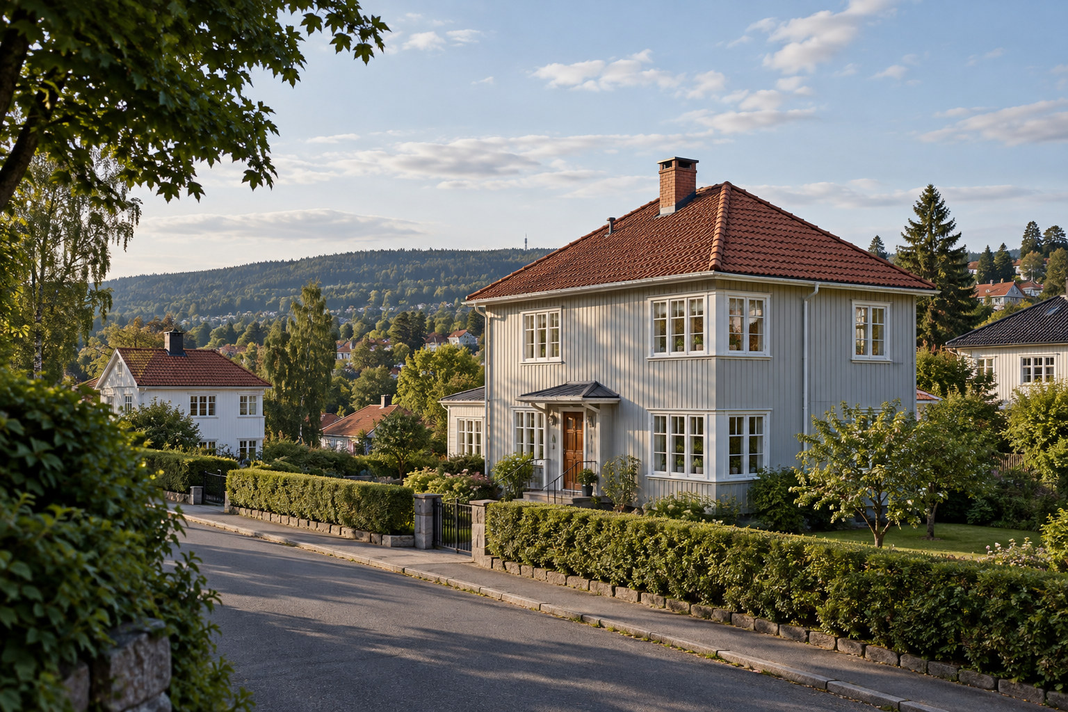 Lys grå trevilla med hvite vinduer, rødt valmtak og hage i et grønt boligstrøk