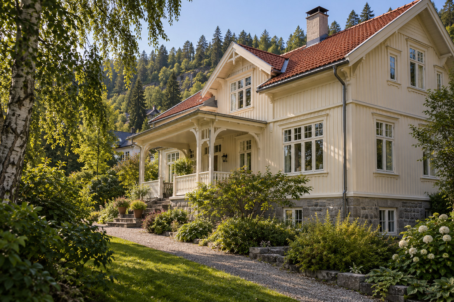 Hvit trevilla med overbygd veranda, rødt tegltak og frodig hage ved en skogkledd åsside